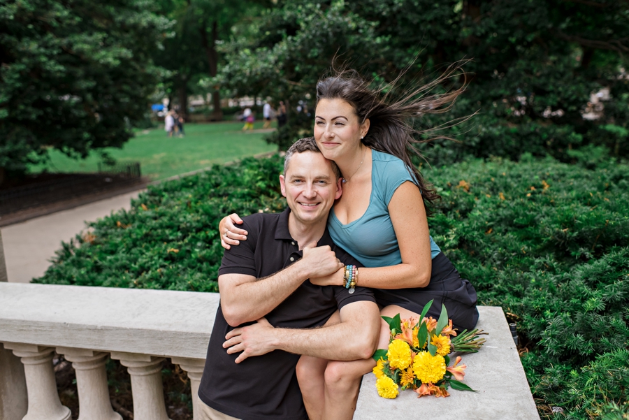 A couple hold each other in Rittenhouse Square while the wind blows through their hair.